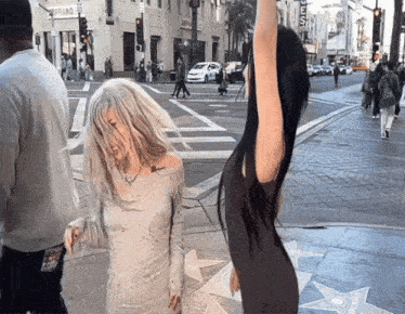 two women are standing on a sidewalk in front of a store that says soprano