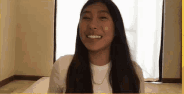 a woman with long hair and a white shirt is smiling