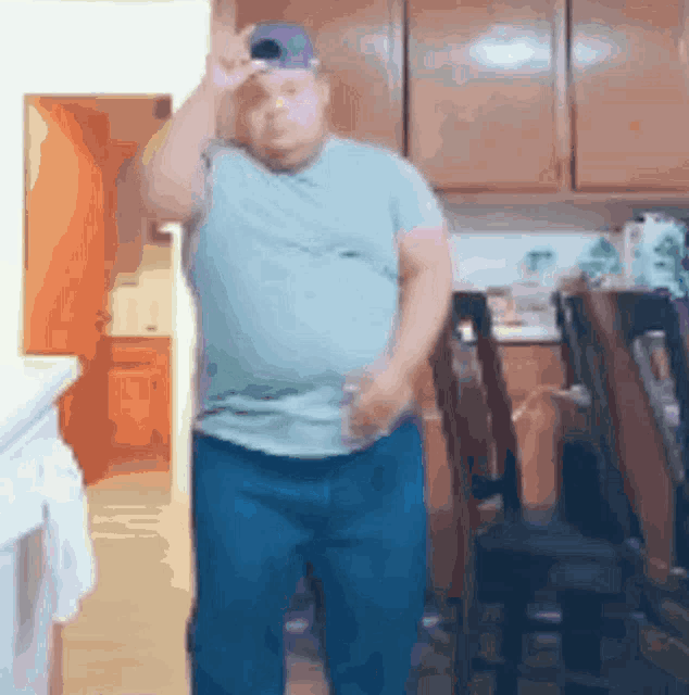 a man standing in a kitchen wearing a hat