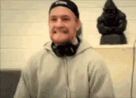 a man wearing headphones and a hat is making a funny face .