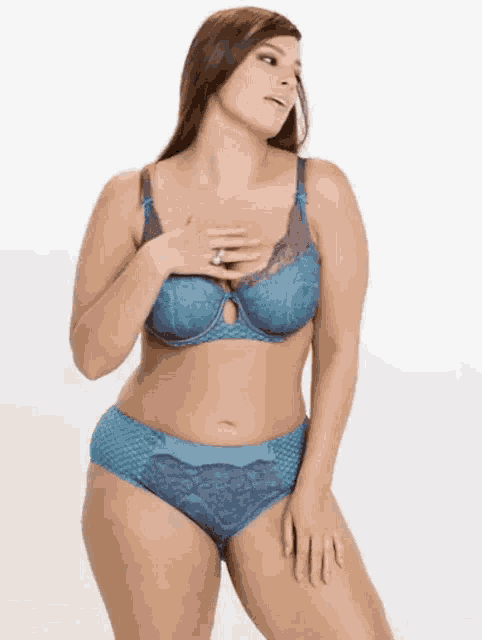 a woman in a blue bra and blue underwear is standing on a white background .