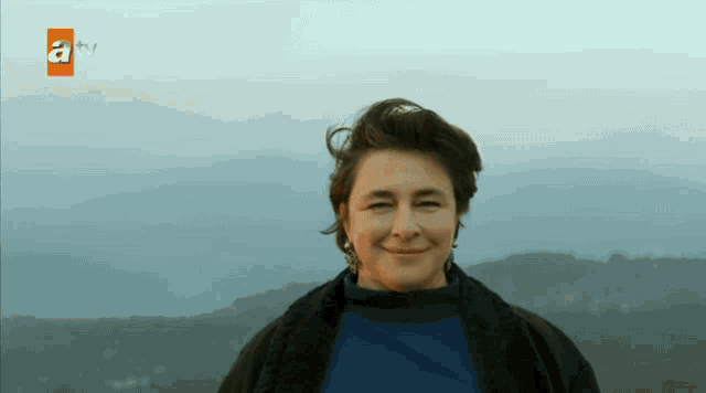 a woman is smiling in front of a tv screen that says atv