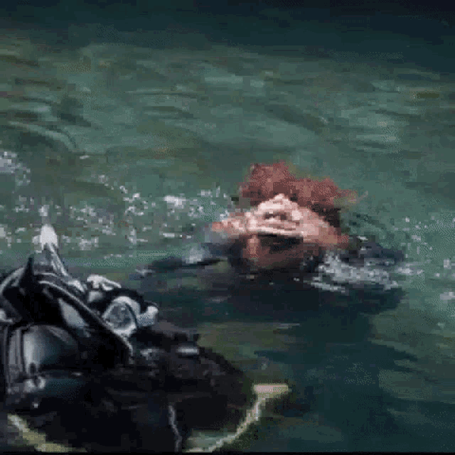 a man is swimming in a body of water with his hands in his mouth .