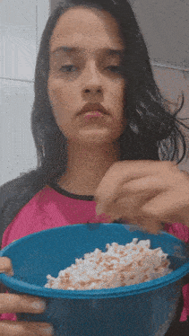 a woman is holding a bowl of popcorn in her hand
