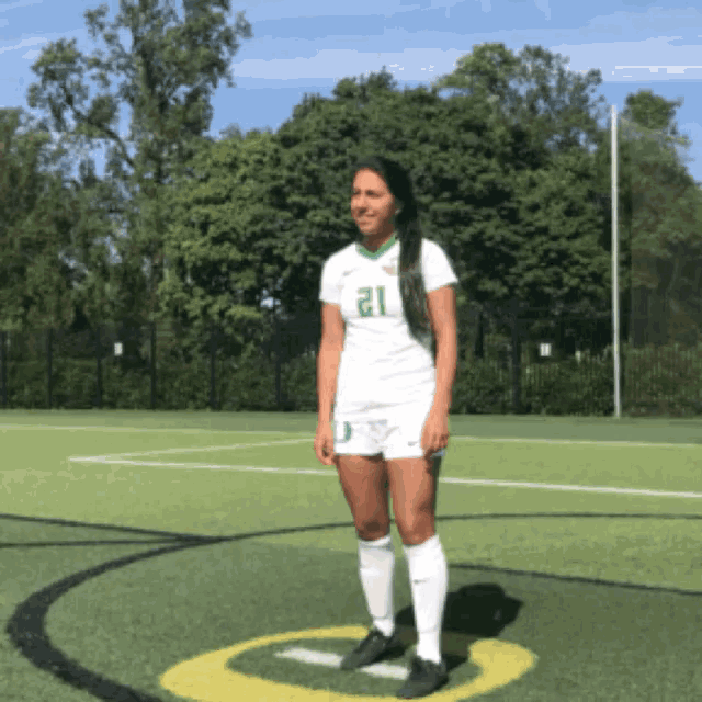 a female soccer player wearing number 21 stands on the field