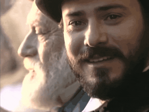 a man with a beard is smiling next to another man with a beard