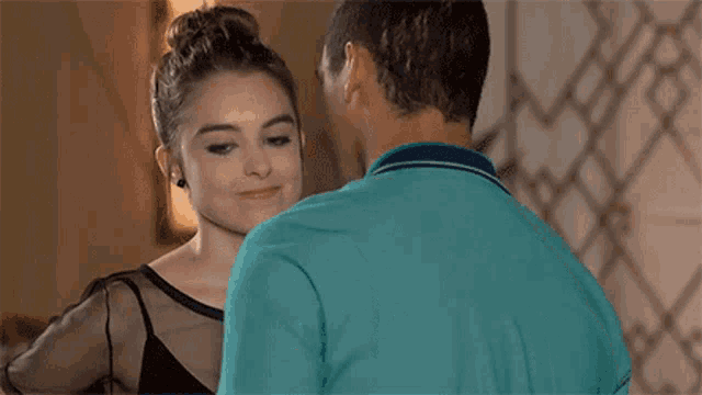 a man and a woman are kissing in a room . the woman is wearing a black top .