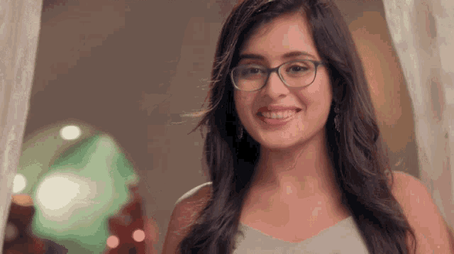 a woman wearing glasses and a white top smiles