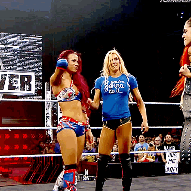 a woman in a blue shirt that says you 're gonna do it stands in a wrestling ring