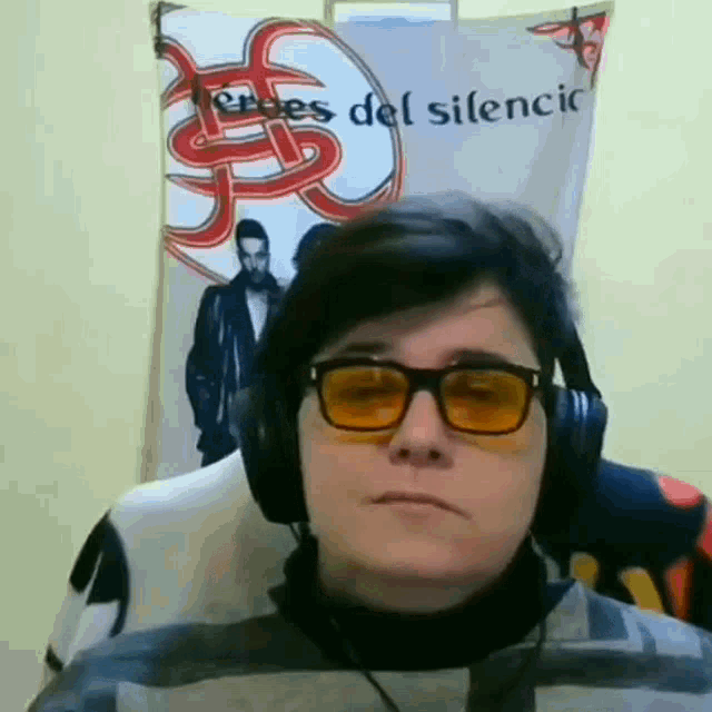 a man wearing headphones and sunglasses is standing in front of a poster that says heroes del silencio
