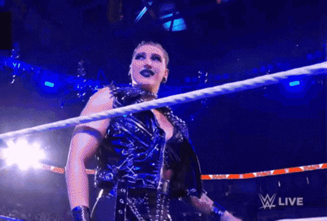 a woman is standing in a wrestling ring with a rope .