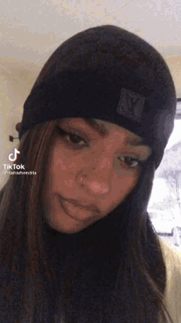 a woman wearing a black beanie with a louis vuitton logo on it