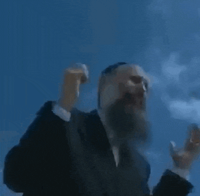 a man with a beard is wearing a suit and tie and smoking a cigarette in front of a blue sky .