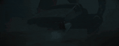 darth vader is standing in a dark room with a red light behind him .