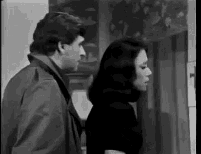 a man and woman are standing next to each other in a black and white photo .