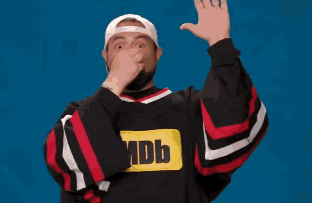 a man wearing a imdb sweater covering his nose with his hand
