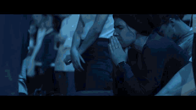 a woman with a ring on her finger praying in a dark room