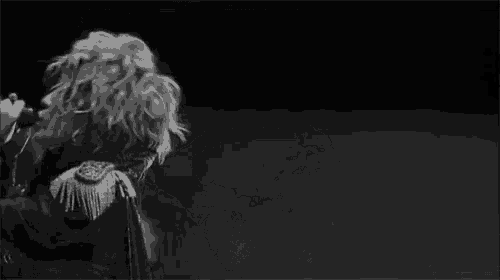 a man is singing into a microphone in a black and white photo .