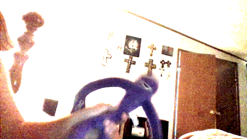 a blurred image of a person holding a steering wheel in a room with crosses on the wall
