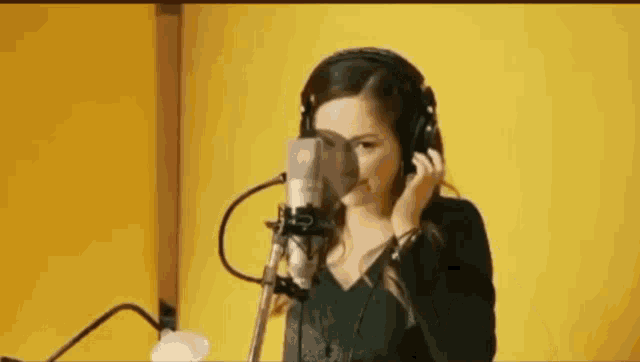 a woman is singing into a microphone while wearing headphones .