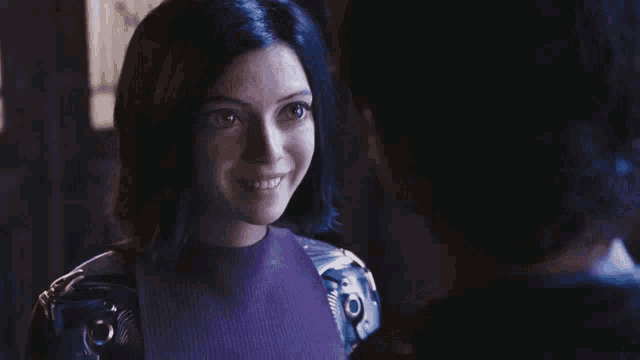 a man and a woman are looking at each other in a dark room and smiling .