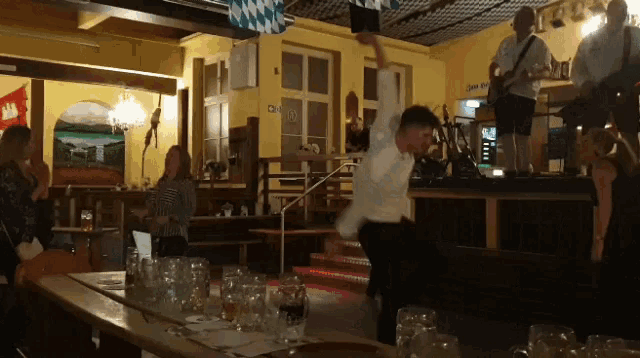 a man in a white shirt is dancing in a room with a sign on the wall that says see de