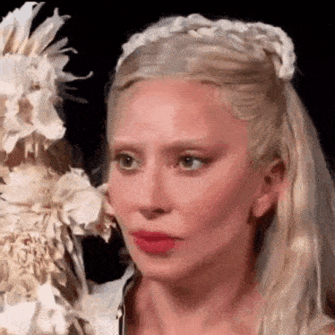 a woman with blonde hair is holding a bouquet of white flowers in her hand .