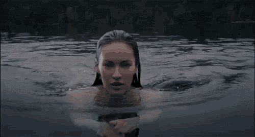 a woman is swimming in a body of water without a shirt on .