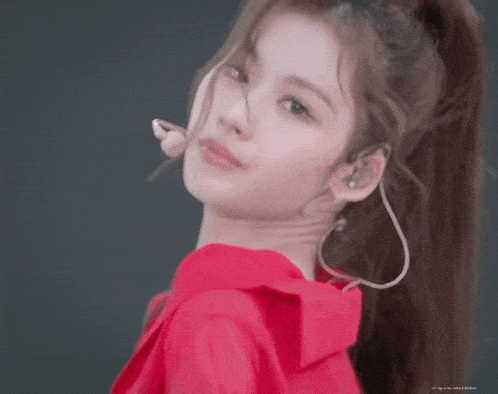 a close up of a woman wearing a red shirt with a ponytail