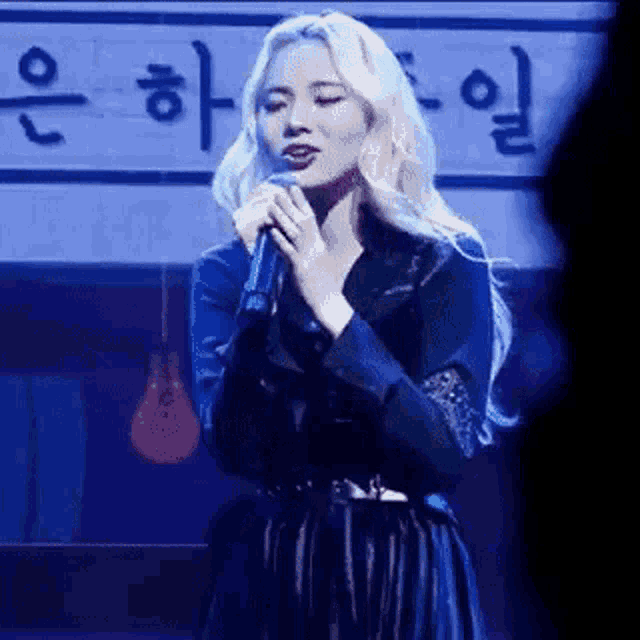 a woman in a blue dress is singing into a microphone on stage .