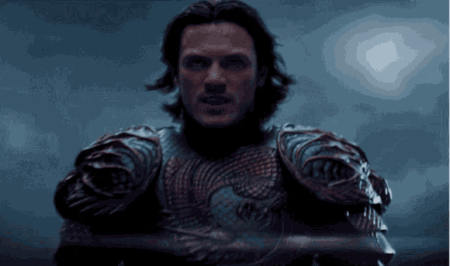a man in armor holds a sword and looks at the camera