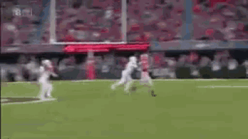 a football game is being played on a field with a crowd watching .