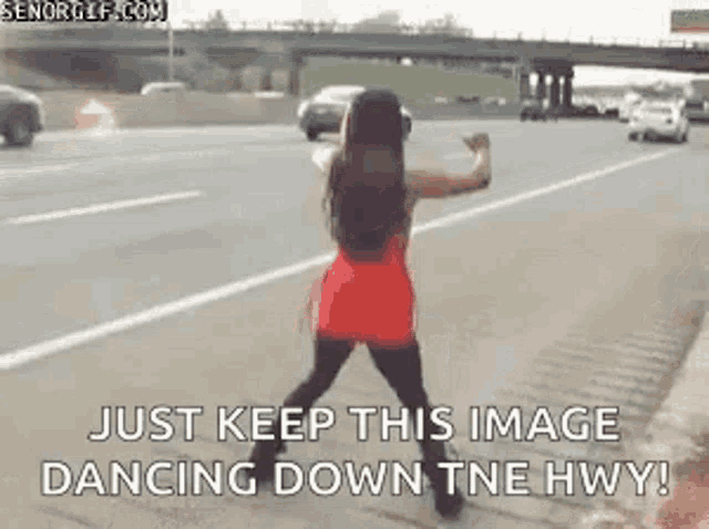a woman in a red dress is dancing on the sidewalk on a highway .