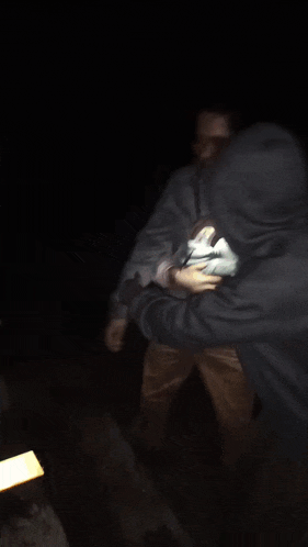 a blurry picture of a man in a gray jacket standing in the dark