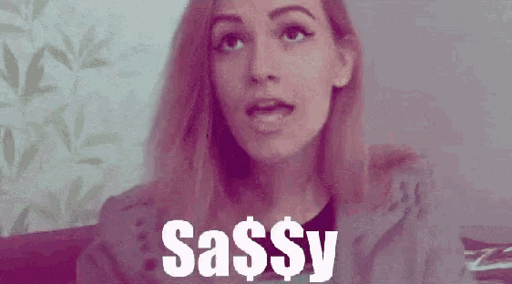 a woman is sitting on a couch with her mouth open and the word sassy is written on the screen .