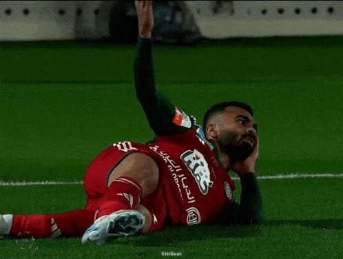 a soccer player laying on the field with a shirt that says ' gtek ' on the back