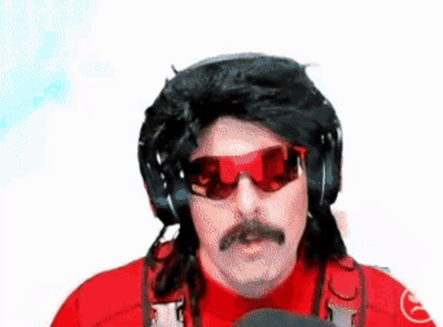 a man wearing a wig , sunglasses , headphones and a mustache is talking into a microphone .