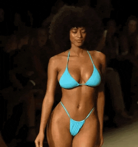a woman in a bikini is walking down the runway at a fashion show .