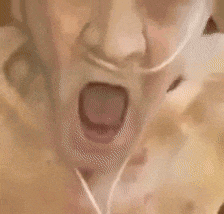 a close up of a man 's face with his mouth open and his tongue out .