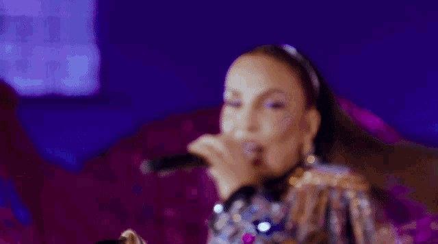 a woman singing into a microphone wearing a fringed jacket