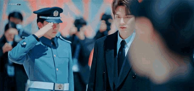 a man in a suit and tie salutes a man in a blue uniform