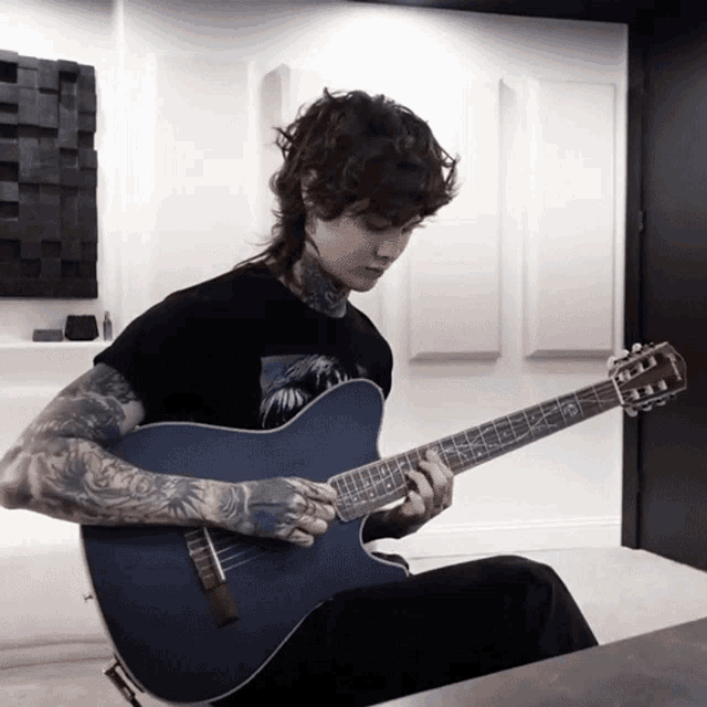 a man in a black shirt is playing a guitar with a fender logo on it