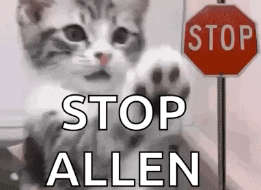 a kitten is standing next to a stop sign and waving its paw .
