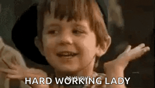 a little boy is smiling and saying `` hard working lady '' with his hands outstretched .