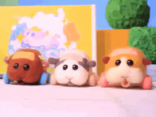 three stuffed animals are sitting next to each other on a table in front of a yellow wall .