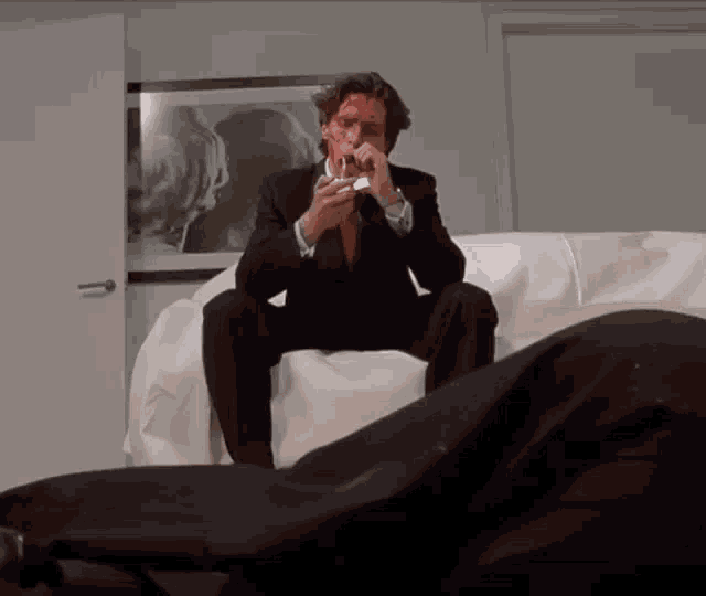 a man in a suit is sitting on a couch with blood on his face