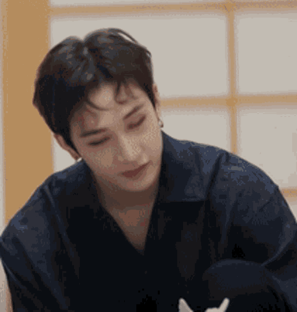 a man in a blue shirt is sitting down with his eyes closed