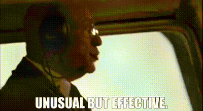 a man in a suit and tie is wearing headphones and looking out the window of an airplane .
