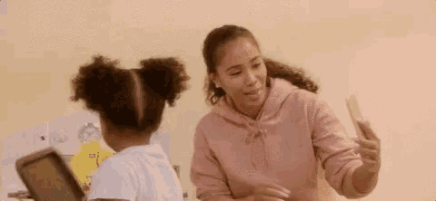 a woman is teaching a little girl how to use a tablet .