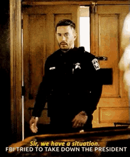 a man in a police uniform is standing in front of a door and talking to someone .